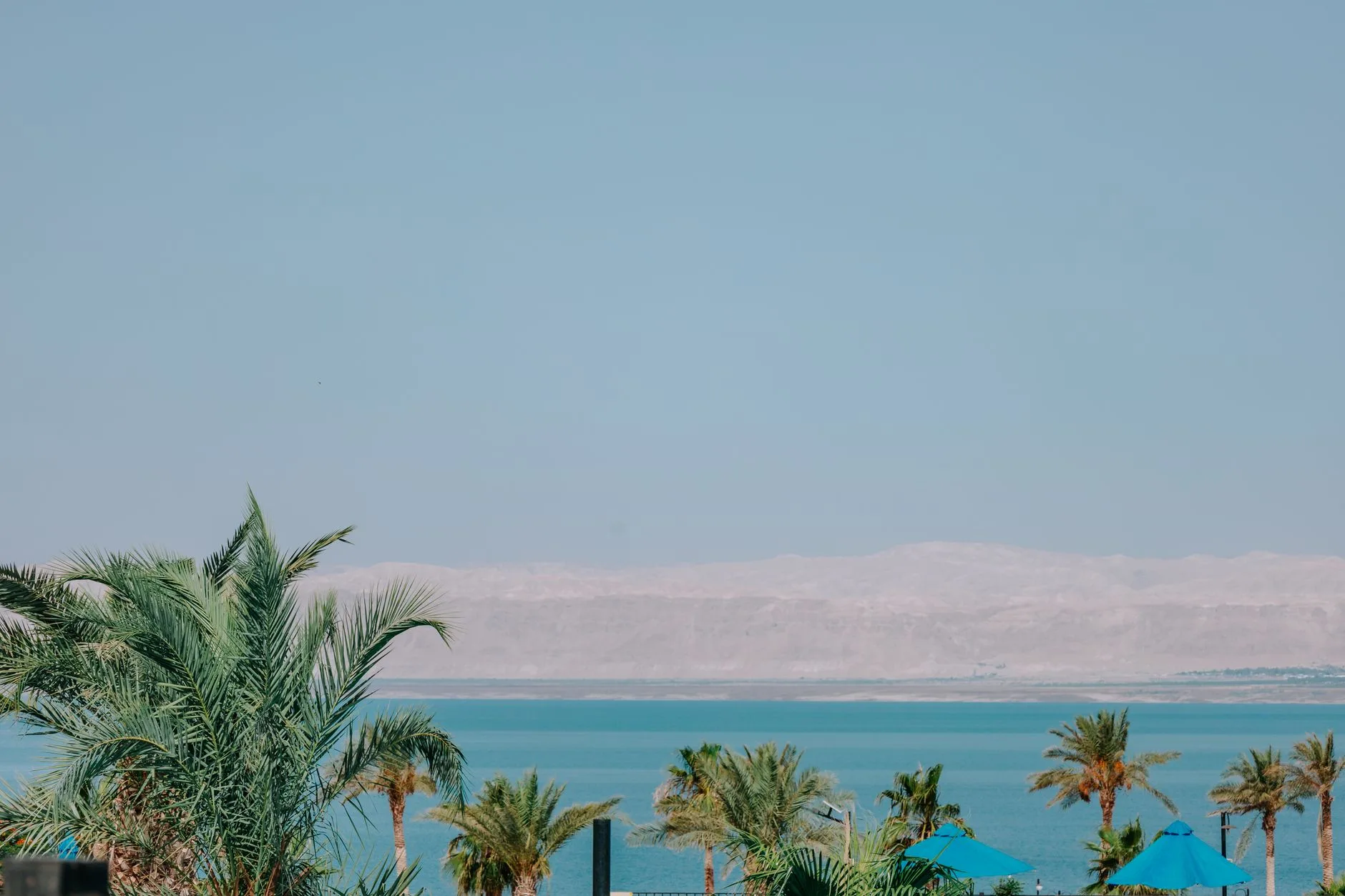 Les eaux bleu-vert salées de la Mer Morte vues depuis la rive jordanienne, avec les montagnes de Judée en arrière-plan